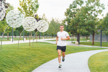 Young sports athlete man in white t-shirt run in the morning in modern park.