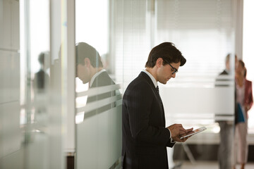 Businessman using digital tablet in office hallway