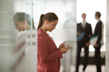 Businesswoman using digital tablet in office hallway