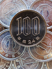 100 yen lies on a pyramid of Japanese 1 yen coins. Close up. View from above. Catchy bright vertical illustration. News about the economy, money and finance of Japan. Macro