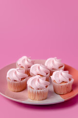 A plate of strawberry pink mini cupcakes on a pink background