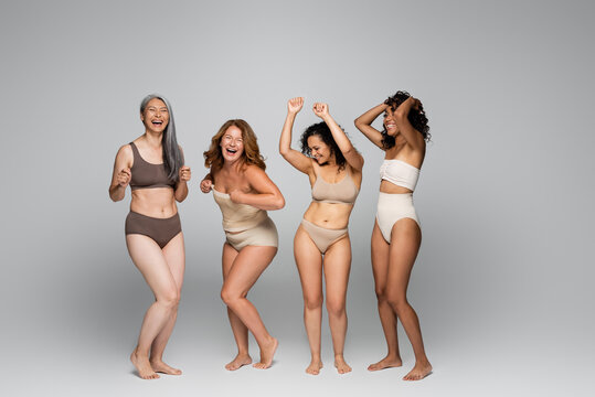 Positive interracial women in underwear on grey background