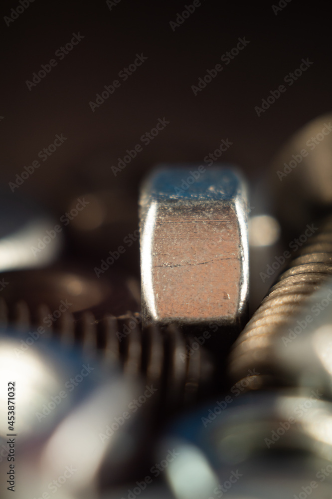 Poster Vertical shot of a metal nut on the screws against a gray background