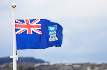 Wind blown tattered Falkland Islands flag with a cloudy sky. Some Motion Blur
