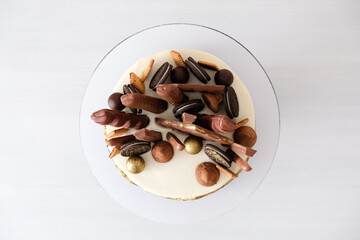 Cake on birthday on a white background decorated with chocolate, chip cookies, candies, bars, truffle and gold. Top view.