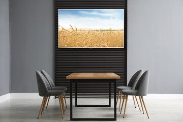 Modern wide screen TV on wall in room with stylish furniture