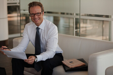 Fototapeta premium Businessman sitting on sofa in office lobby