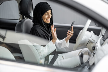 Muslim woman talks on phone while driving a car