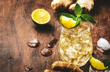 Classic Ginger Ale Cocktails with Beer, Lime, Lemon and Mint Leaves in glaasses on wooden table, negative space