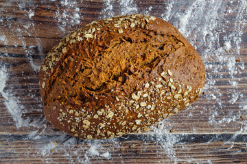 A loaf of whole wheat bread with cereal flakes. Flat lay.