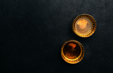 American bourbon whiskey in glasses, black background with negative space