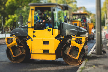 Process of asphalting, blacktopping and paving, asphalt paver machine and steam roller compactor during construction and repairing works, workers on the construction site, rental vehicle working