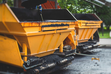 Obraz na płótnie Canvas Process of asphalting, blacktopping and paving, asphalt paver machine and steam roller compactor during construction and repairing works, workers on the construction site, rental vehicle working