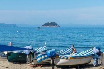 Fototapeta na wymiar The small beach of Laigueglia with small fishing boats and an island in the background