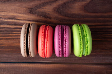 Delicious sweet almond cookies of different colors on a brown wooden background. Top view, flat lay