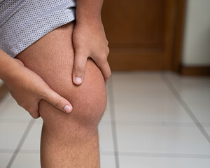 Man massages swollen knee caused by gout attack