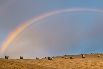 Hay bales ready for collection as a rainbow appears in the sky

