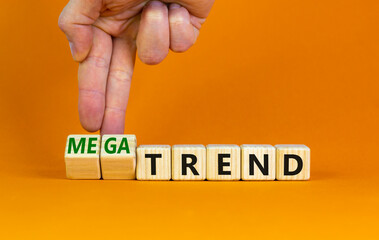 Trend or megatrend symbol. Businessman turns wooden cubes and changes words trend to megatrend. Beautiful orange table, orange background, copy space. Business, trend or megatrend concept.