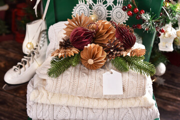 Stack of wool sweaters and diy paper ornaments in front of Christmas tree