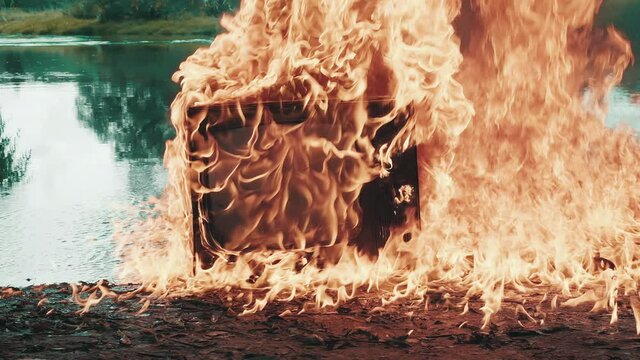 Retro vintage TV set against the background of river explodes beautifully with clouds of fire. Water is also burning. Concept of post apocalypse, surrealism and fire hazard of old worn out equipment