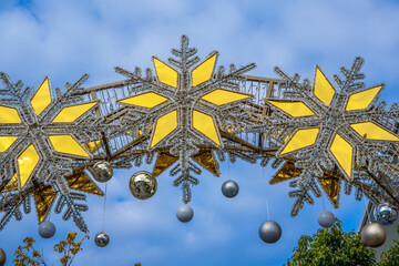 Silver gold Christmas stars in front of blue cloudy sky. Winter holiday decorations. High quality photo
