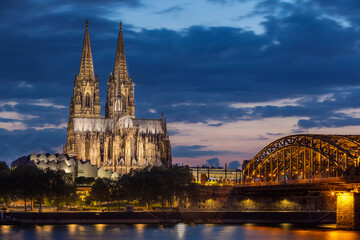 Naklejka premium Historical buildings illuminated against blue hour sky late in summer in Cologne