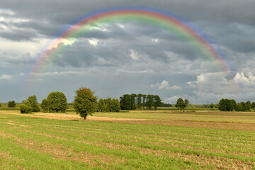 Beautiful countryside landscape with rainbow on the sky