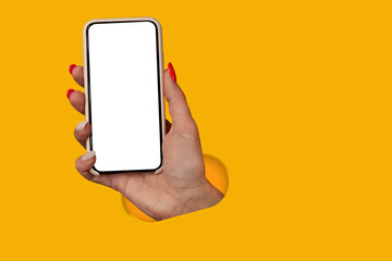 Woman holding in hand smartphone with blank screen isolated on yellow background. Creative technology concept.