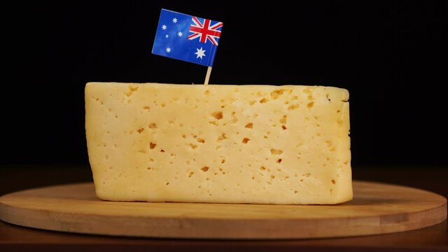 Man's hand put small in size toothpick with australian flag on cheese.