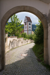 Fototapeta premium Catholic parish church of St. Mang through an arch in old town of Fussen, Bavaria, Germany