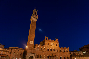 Fototapeta premium The Torre del Mangia and the Palazzo Pubblico at night, from across the Piazza del Campo, Siena, Tuscany, Italy