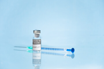 Vial, frasco y jeringa con medicamento vacuna Covid-19 fondo azul claro