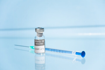 Vial, frasco y jeringa con medicamento vacuna Covid-19 fondo azul claro