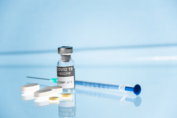 Vial, frasco y jeringa con medicamento vacuna Covid-19 fondo azul claro
