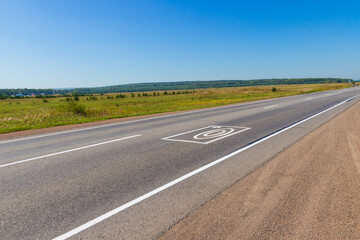 Naklejka premium Summer landscape with rural road. Photo and video recording markings on the asphalt warns about the complex for automatic recording of offenses on the road by drivers