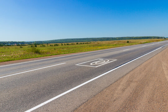 Summer landscape with rural road. Photo and video recording markings on the asphalt warns about the complex for automatic recording of offenses on the road by drivers