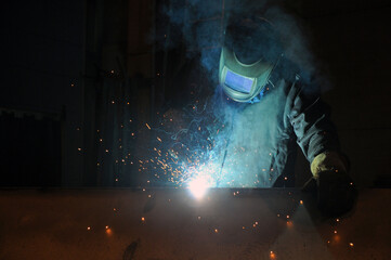 Fototapeta na wymiar An electric welder welds metal structures at a factory.