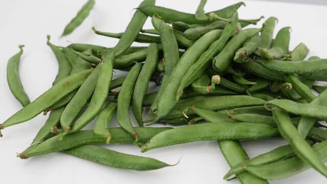 Macro shot of falling green beans on white background