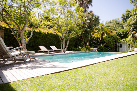 Lawn chairs and swimming pool in backyard