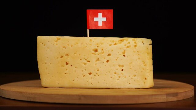 Man's hand put small in size toothpick with swiss flag on cheese.