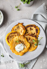 Fried patisson or yellow zucchini with sauce and micro greens, grey concrete background.
