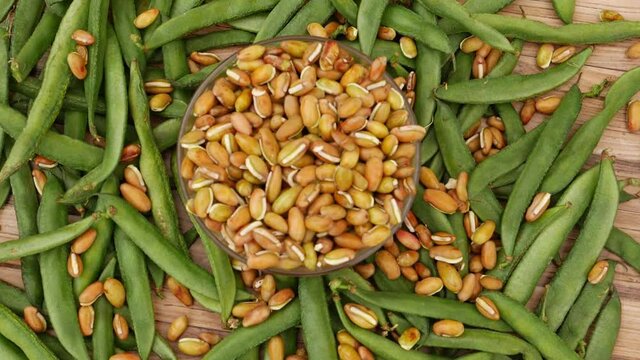 Beans Seeds Falling Over Transparent Glass With Green Beans Around