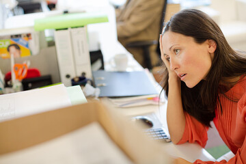 Obraz na płótnie Canvas Businesswoman resting chin in hand on desk