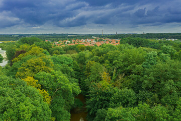 Fototapeta na wymiar Dachy osiedla domów jednorodzinnych pośród zieleni otaczających je lasów. Widok z drona.