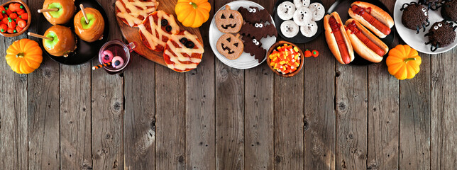 Halloween party food top border over a rustic wood banner background with copy space. Above view....