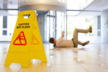 Businessman slipping on wet office floor - obrazy, fototapety, plakaty
