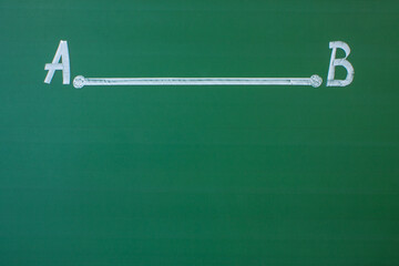 A straight segment with two points A and B drawn in white chalk on a green blackboard close-up and space for copying