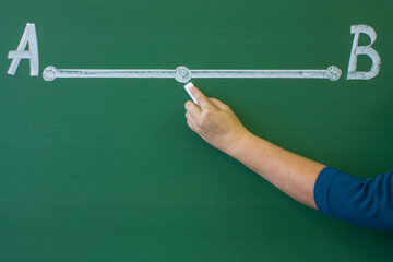 A mathematical segment drawn in white chalk on the blackboard in close-up and the hand of a teacher explaining a math problem. Concept-a class lesson and a space for copying