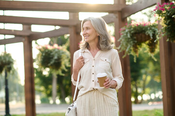 Smiling confident woman with handbag and coffee
