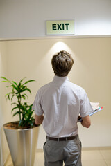 Businessman examining exit sign in office